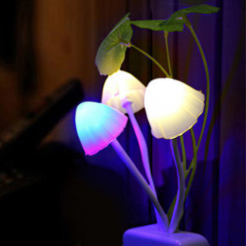 Color LED mushroom light with white pot and green leaves glowing in pink, yellow, and purple colors